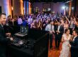 Modern professional DJ setup with clean audio equipment and elegant warm uplighting at a wedding reception