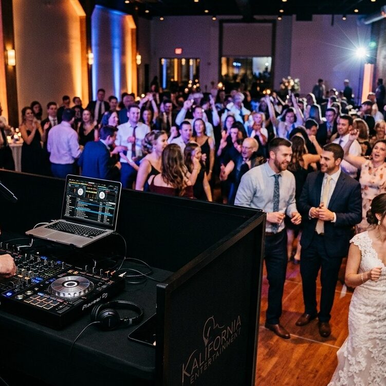 Professional Wedding DJ and Uplighting Setup at Reception Modern professional DJ setup with clean audio equipment and elegant warm uplighting at a wedding reception