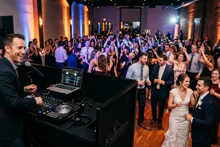 Modern professional DJ setup with clean audio equipment and elegant warm uplighting at a wedding reception