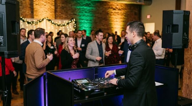 A professional DJ with modern equipment and dynamic uplighting entertains a lively corporate holiday party crowd in Rochester NY.