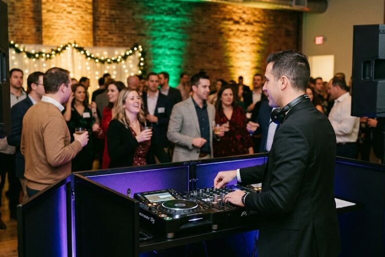 A professional DJ with modern equipment and dynamic uplighting entertains a lively corporate holiday party crowd in Rochester NY.
