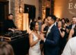 A smiling bride and groom dancing on a packed dance floor during a wedding reception with a professional wedding DJ and custom monogram lighting in Rochester NY.